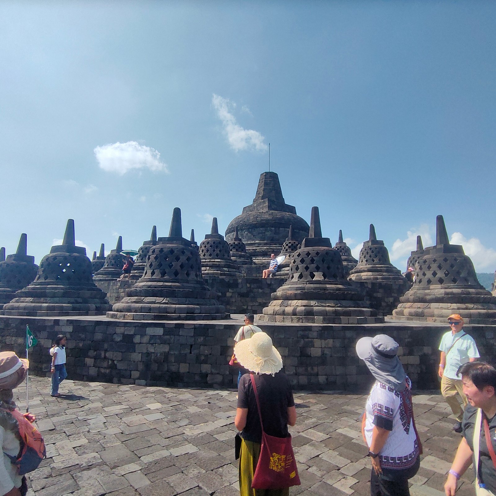 Borobudur temple upper terrace with central dome and multiple bell shaped stupas surrounded by tourists Central Java Indonesia