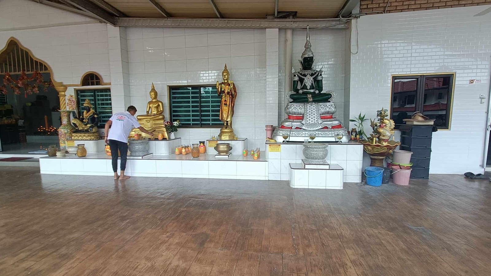 Prayer hall
`Inside the main prayer hall of Wat Puthanimittam Temple Ipoh with golden Buddha statues and a person praying at the altar`