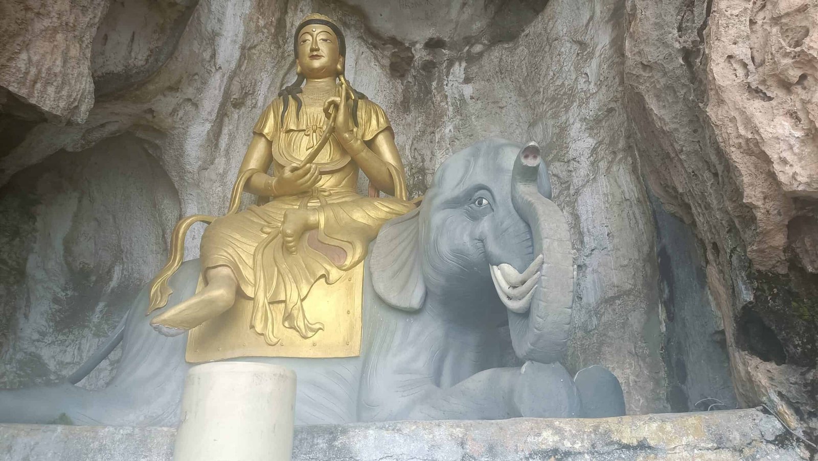 Golden deity statue seated on a grey elephant inside Perak Tong Cave Temple