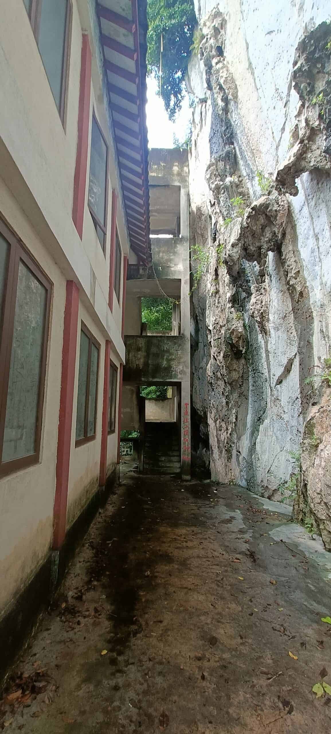 Narrow pathway between temple building and limestone rock wall at Perak Tong Cave Temple