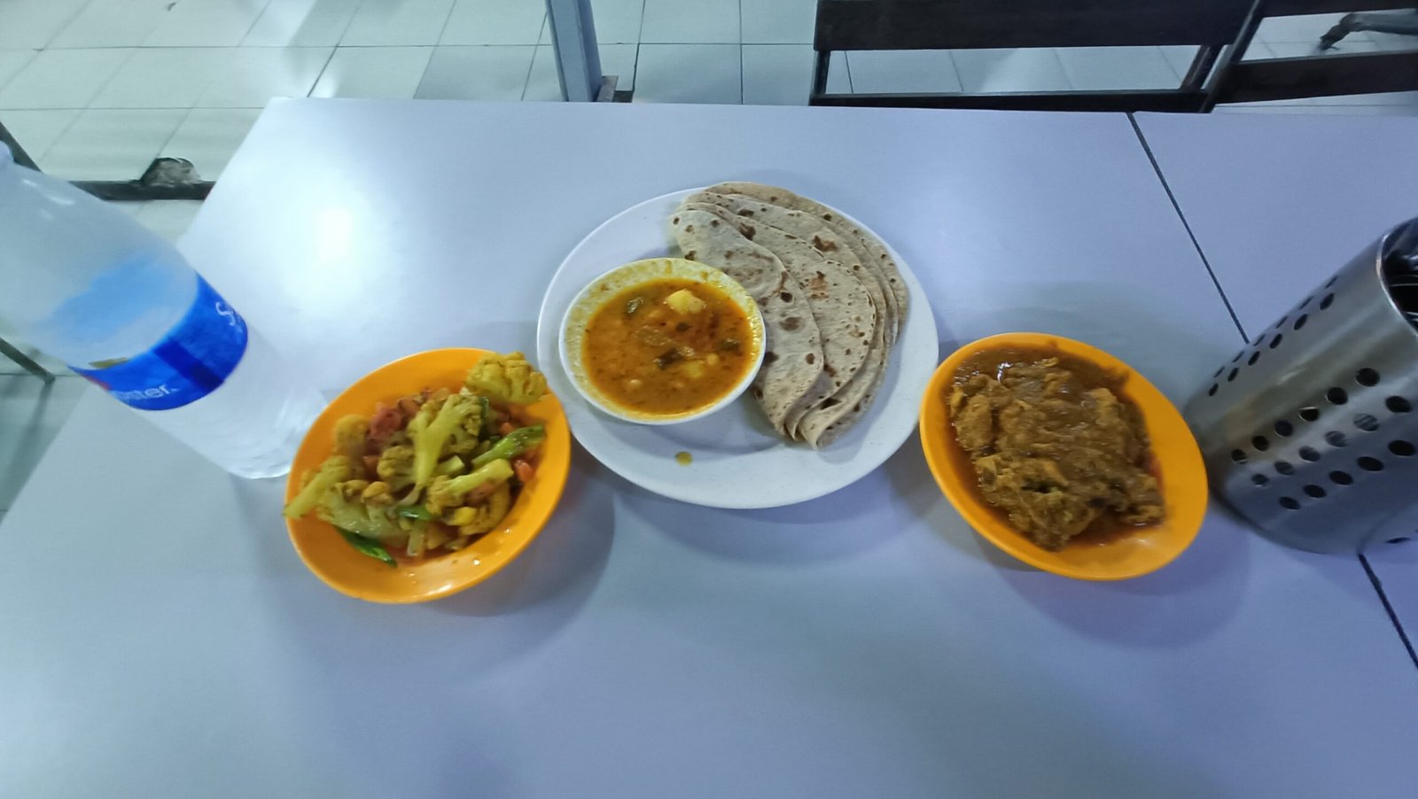 4 Chapati with dhal on center, curry chicken on the right side. With veg to balance and water to cool down.